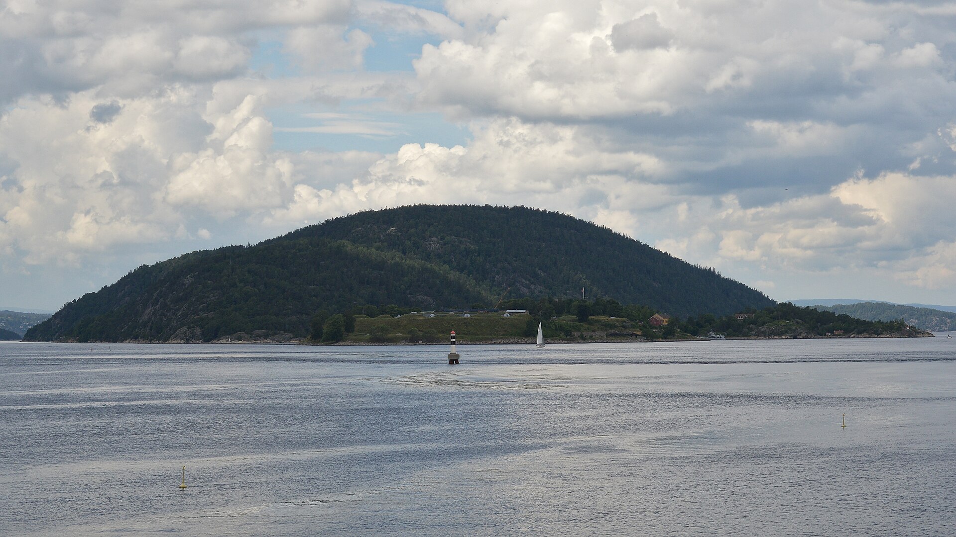 Håøya sett fra Oslofjorden en sommerdag — skogkledd øy med Oscarsborg ved foten